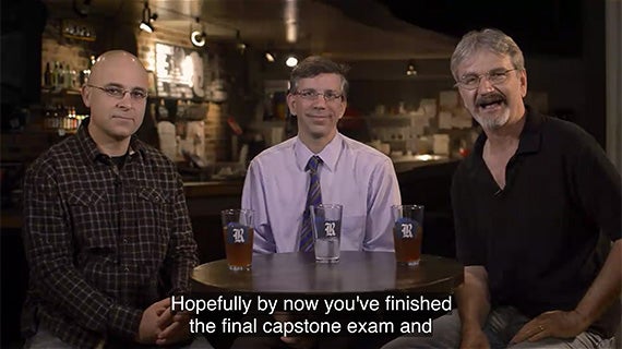 Three men seated at a table, each with a beer in front of them, engaged in conversation and enjoying their time together.