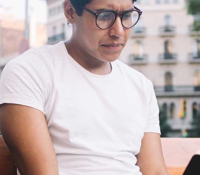 a man with glasses reading a book in public 