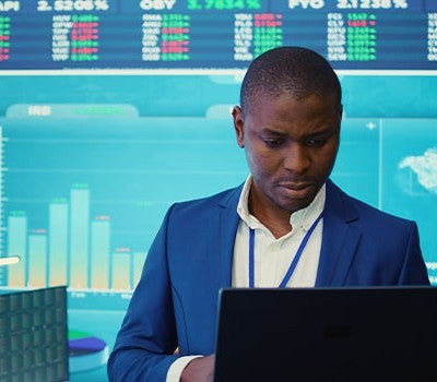 A man in a suit intently gazes at a laptop screen, focused on his work or research.