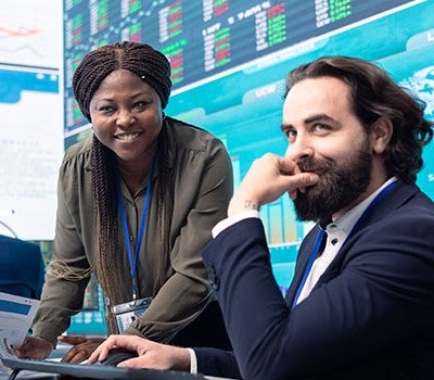A man and woman are seated at a desk, engaged in conversation and collaborating on a project.